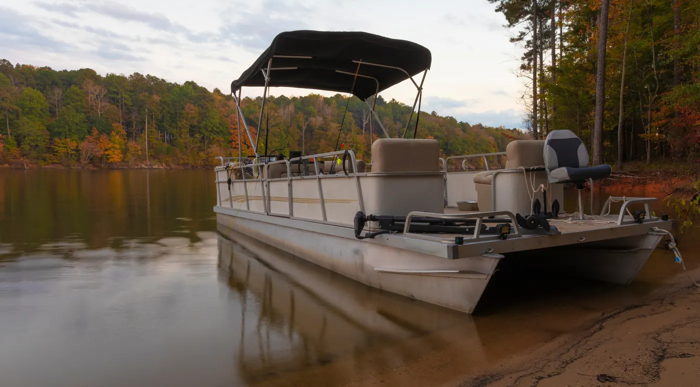 A pontoon boat pulled up on a lake shore