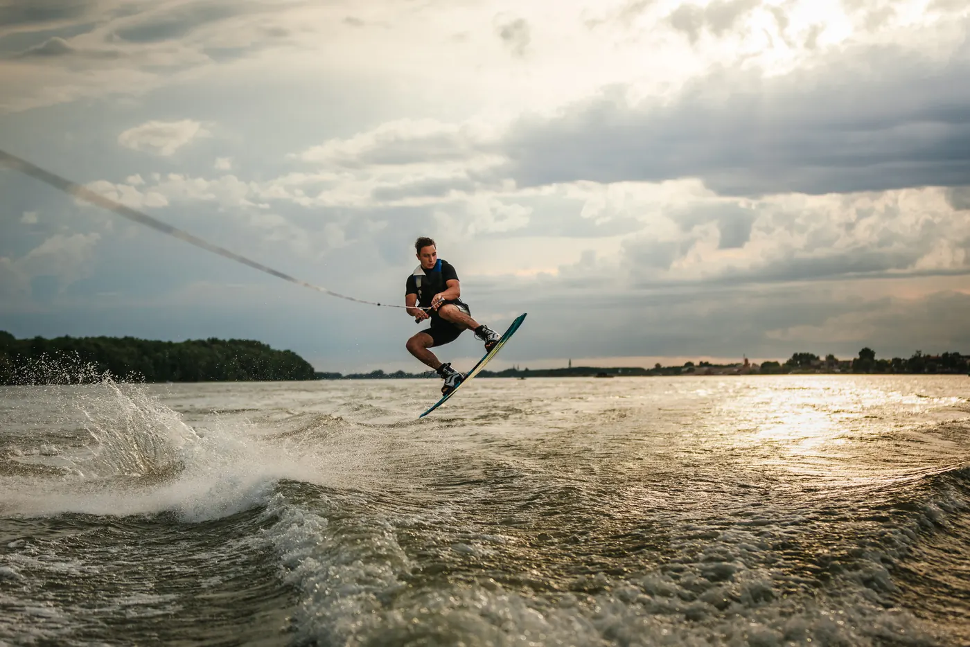 A wakeboarder carving behind a boat at golden hour